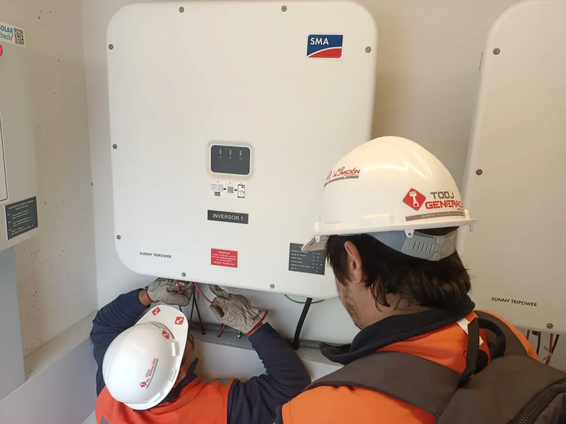 Técnicos conectando el inversor de un sistema fotovoltaico conectado a la red
